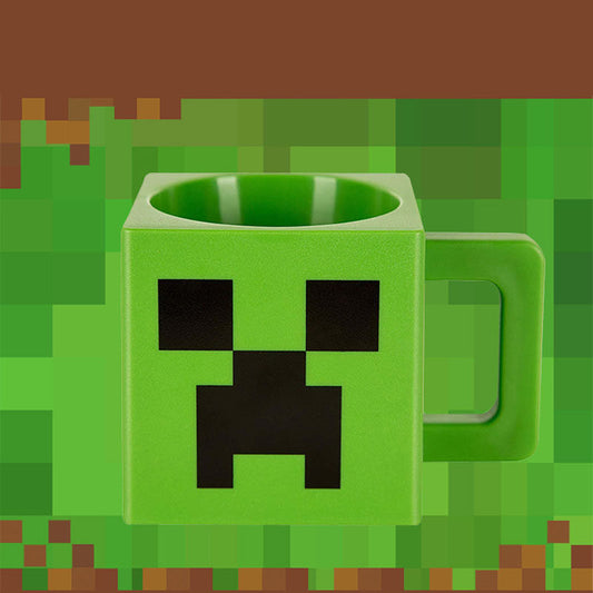 Green Minecraft Creeper pixel mug close-up, with block body and iconic Creeper face, against pixelated grassy blocks.