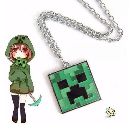 Green pixelated Minecraft Creeper face metal pendant necklace, featuring the iconic mob's blocky design, displayed against a light brown marble texture background.