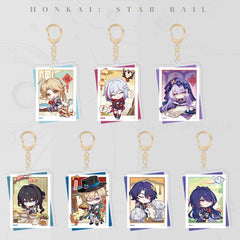 A full set of seven Honkai: Star Rail polaroid-style acrylic keychains, each with a gold clasp. They feature chibi characters with festive and casual designs, laid out in a grid.