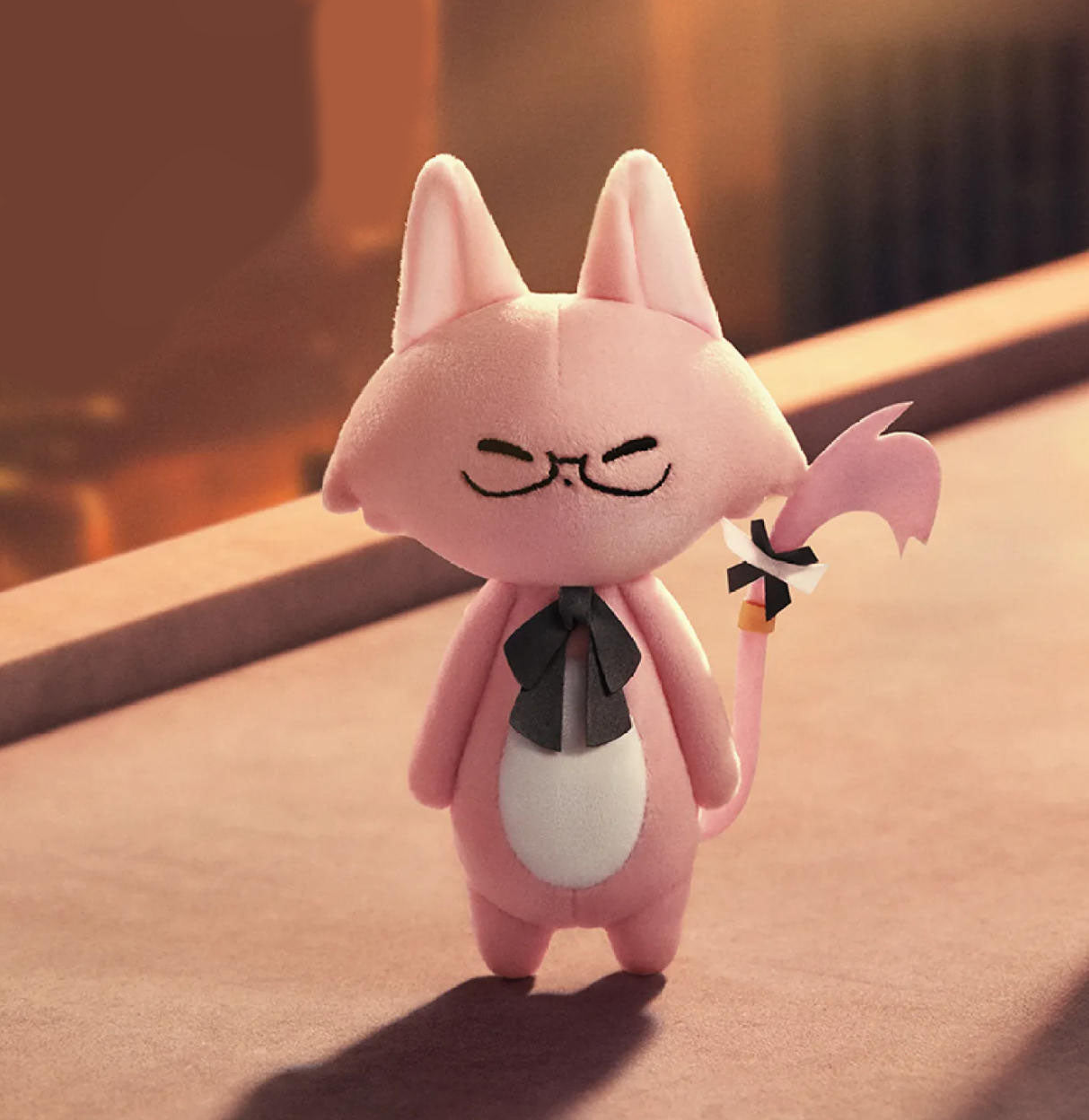 This is a pink cat doll. It has pointed pink ears, closed eyes with black curved lines, a black bow tie around its neck, and an oval white patch on its belly. 