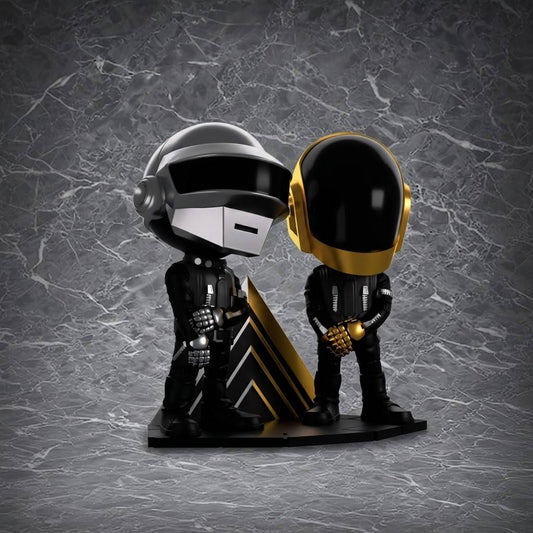 Two chibi-style figures in futuristic black-and-silver and black-and-gold helmets stand side by side on a geometric triangular base, set against a gray marble background with white veining