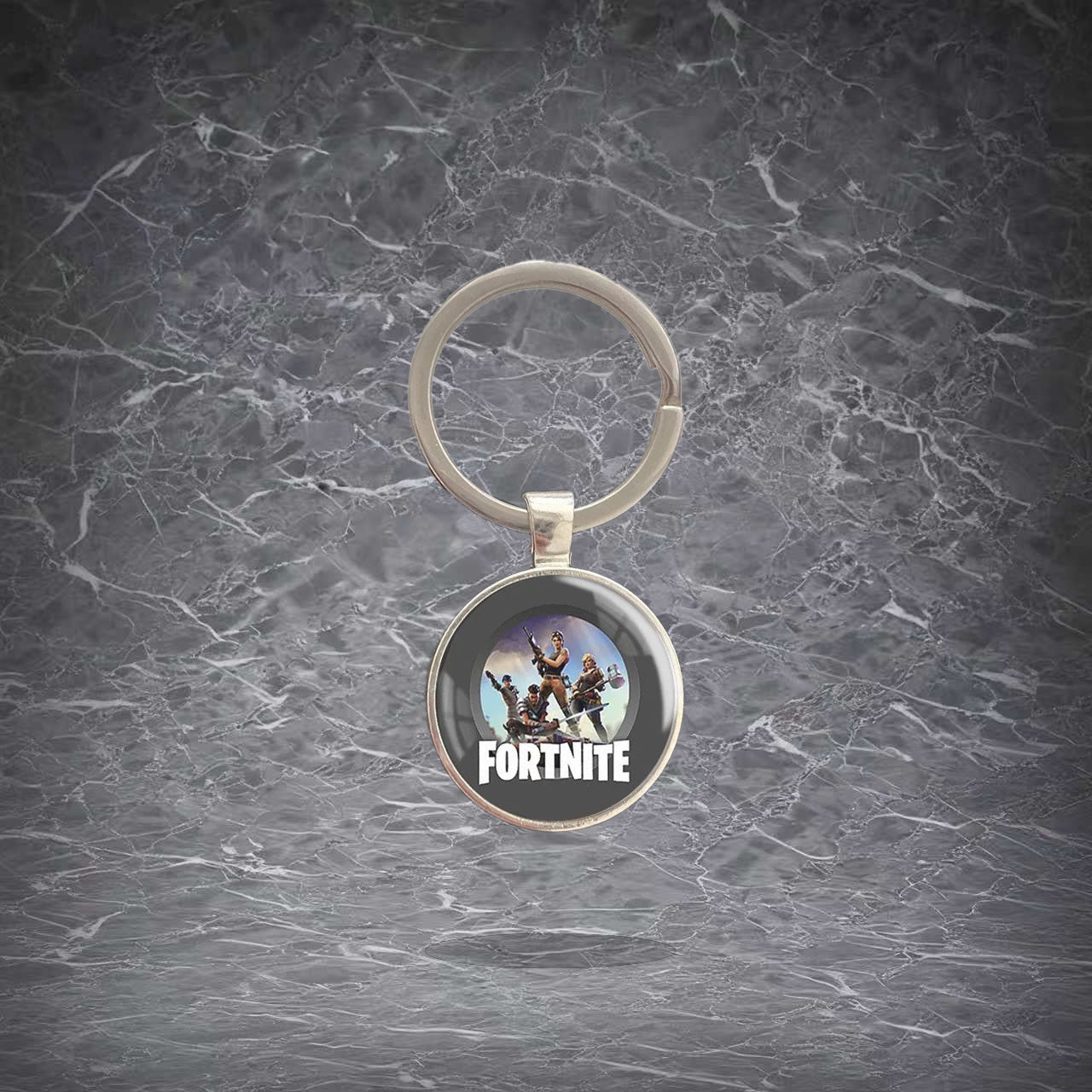 Round Fortnite-themed keychain featuring character artwork and the game logo, set in a shiny metal frame with a sturdy split ring. Lightweight, scratch-resistant pendant for keys, backpacks, and bags. Ideal for fans to show off their love for the game.