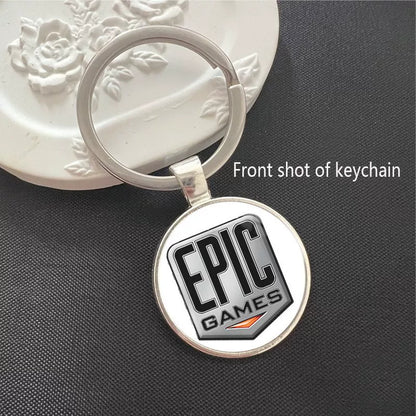 Epic Games logo keychain featuring the iconic brand design on a clean white background. Encased in a polished silver frame with a scratch-resistant dome, ideal for keys or backpacks.