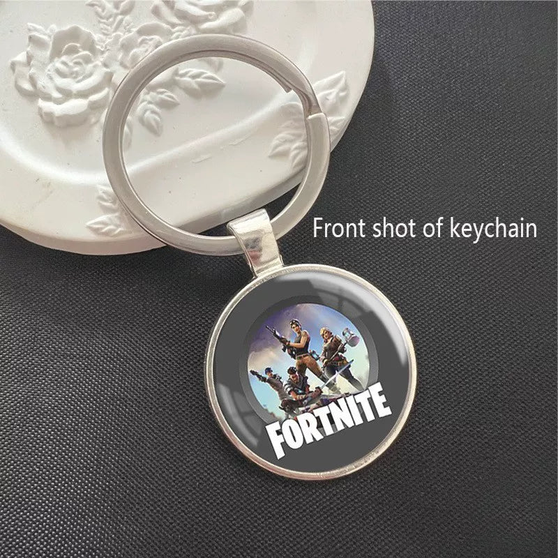 Round Fortnite-themed keychain featuring game character art and logo, set in a shiny silver metal frame with a sturdy split ring. The scratch-resistant pendant is lightweight, perfect for attaching to keys, backpacks, or bags. A great accessory for fans to show their love for the game.