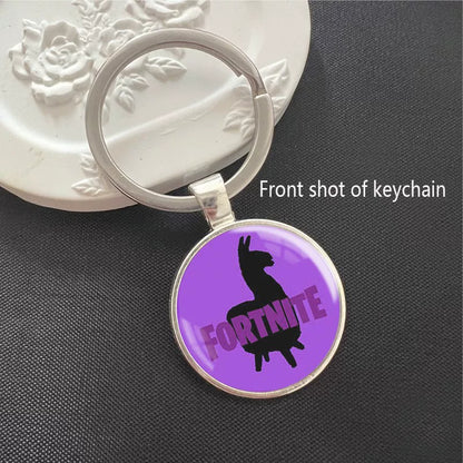 Round Fortnite Battle Royale keychain featuring the iconic game logo with vibrant battlefield artwork, set in a polished silver metal frame. It has a scratch-resistant glass dome cover and a sturdy split ring, perfect for attaching to keys, backpacks, or bags. A fun collectible for fans.