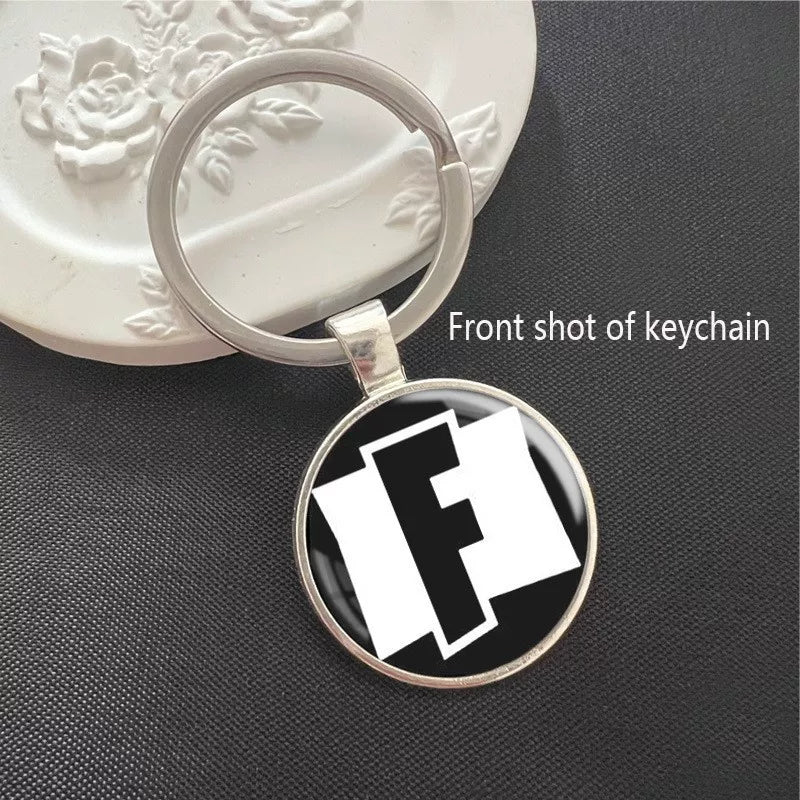 Fortnite logo keychain featuring the iconic stylized F symbol on a black background, set in a polished silver frame with a scratch-resistant dome. Ideal for keys or backpacks.