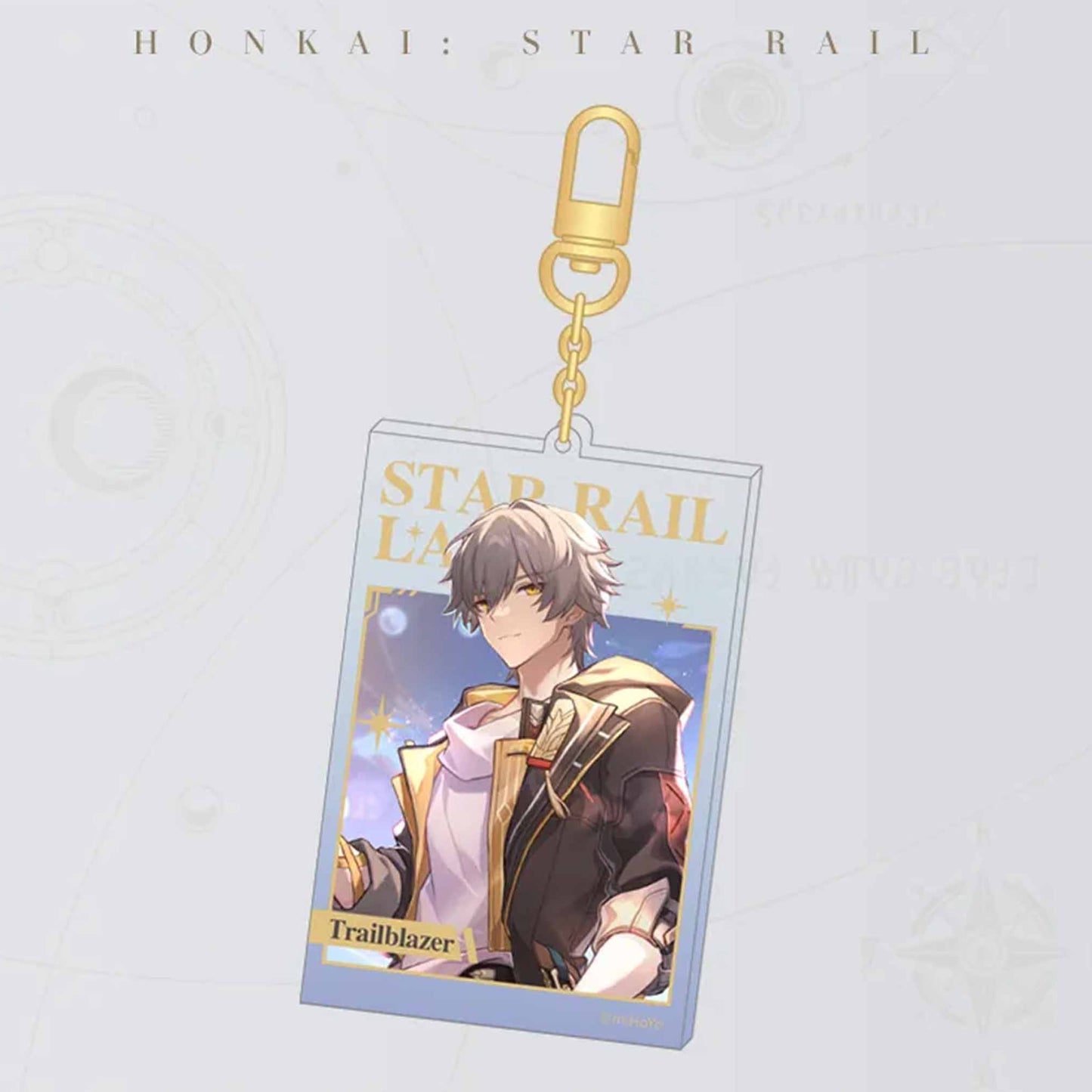 A single Honkai: Star Rail acrylic card keychain with a gold carabiner. It features the male Trailblazer, with “STAR RAIL LANE” in gold foil and the character’s name at the bottom.