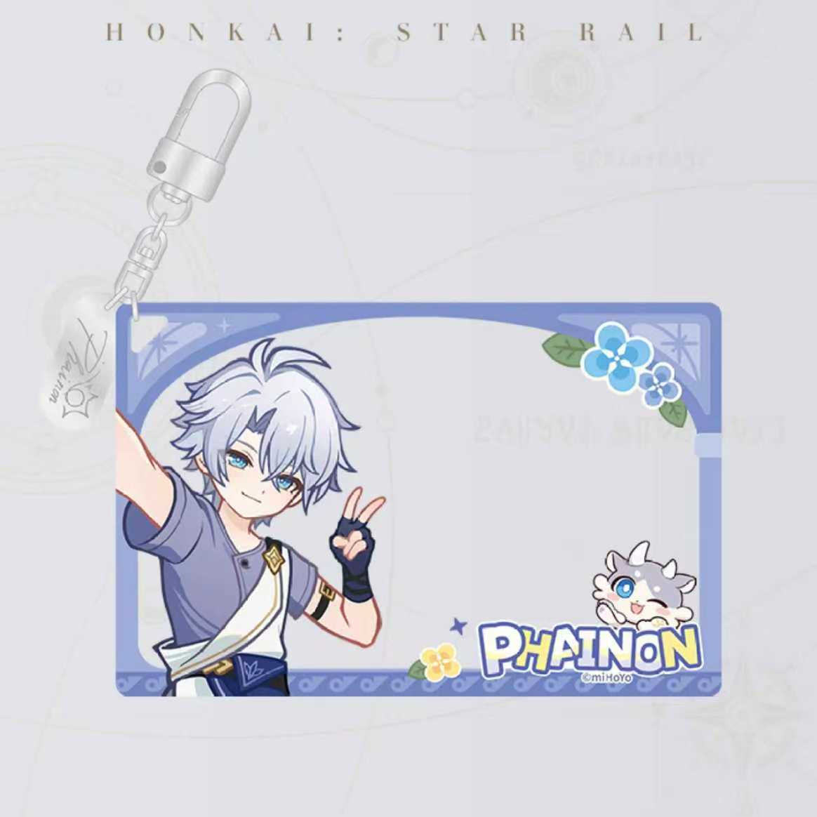 This Honkai: Star Rail acrylic keychain features the character Phainon in a playful chibi style, with a blank space for customization, a silver clasp, and a cute companion character on the side.