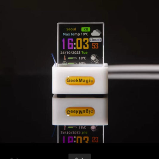 GeekMagic Mini Transparent WiFi Weather Clock. Shows time, date, Seoul weather, and temperature on a vibrant, pixelated screen, with a reflective black backdrop.
