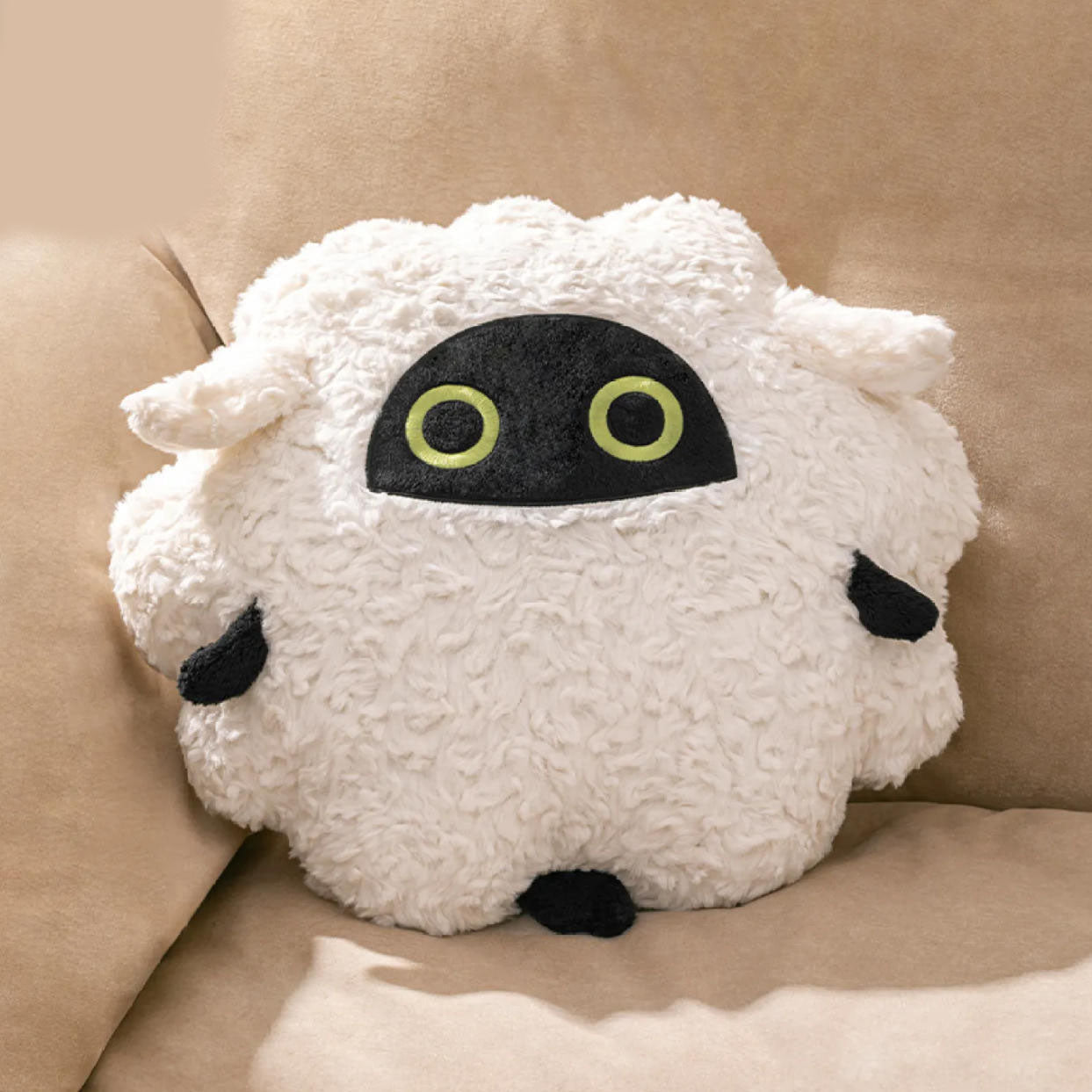 This is a lifestyle shot of the Mewaboo plush pillow .The pillow is nestled against a light brown sofa cushion, showcasing its cozy appearance as a home decor item. 
